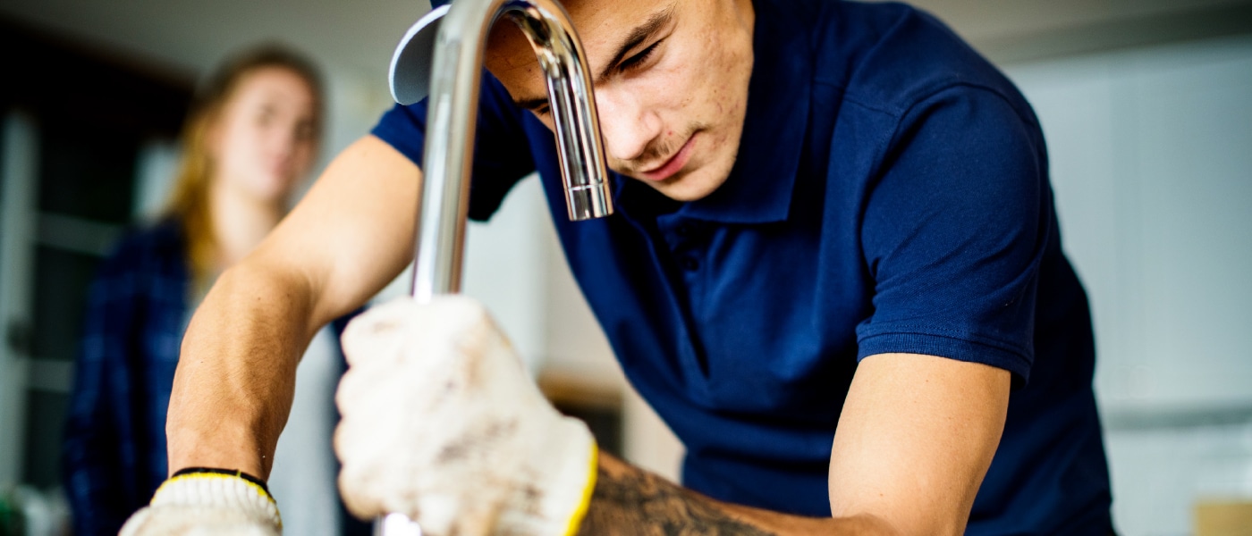 Artisan plombier travaillant sur un robinet.