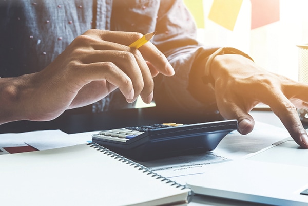 Gros plan sur les mains d’une personne qui fait ses comptes avec une calculatrice.