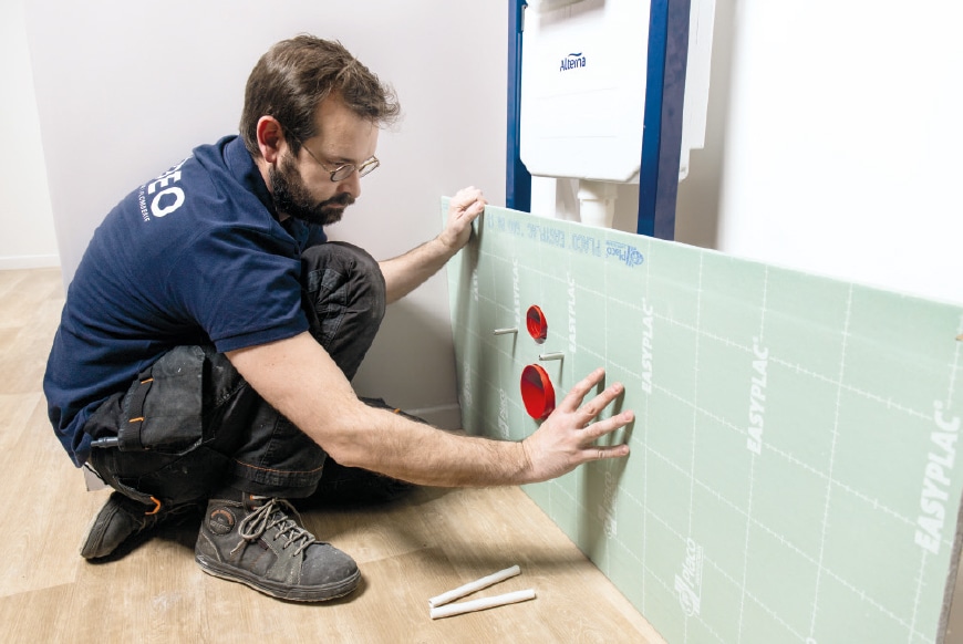 Le plombier pose l’habillage du bâti-support.