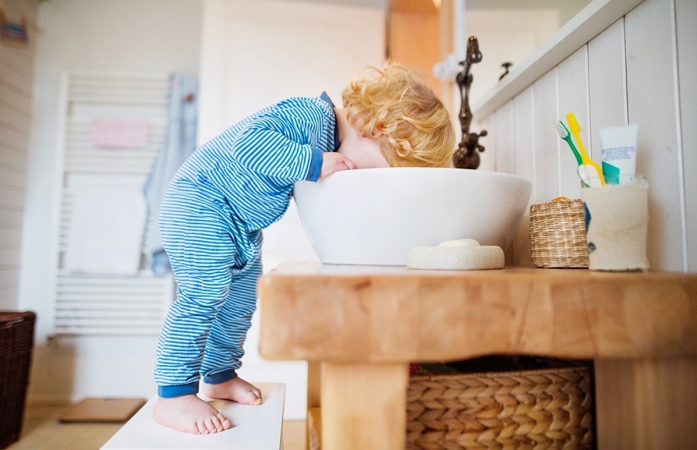 Un jeune enfant boit au robinet